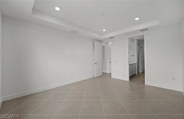 tiled empty room with a tray ceiling