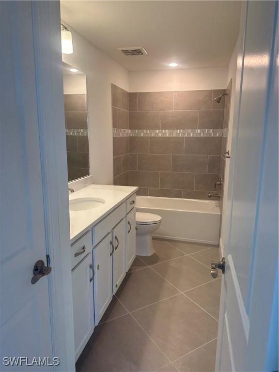 full bathroom with tile patterned floors, vanity, toilet, and tiled shower / bath combo