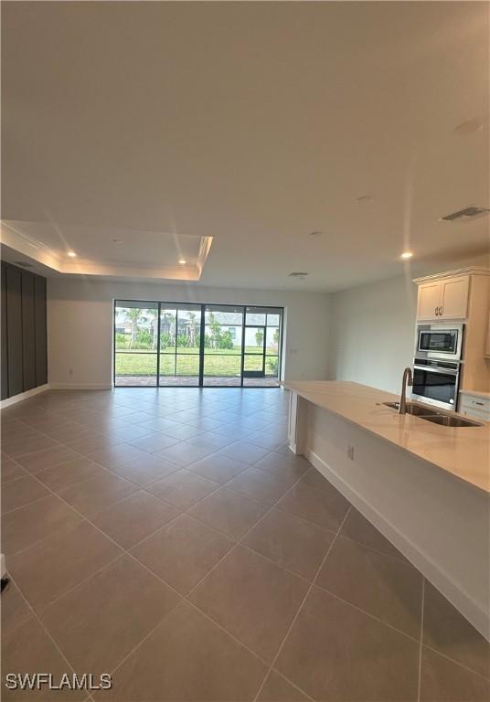 spare room featuring sink, tile patterned floors, and a raised ceiling