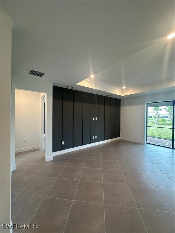 spare room with a raised ceiling and tile patterned floors