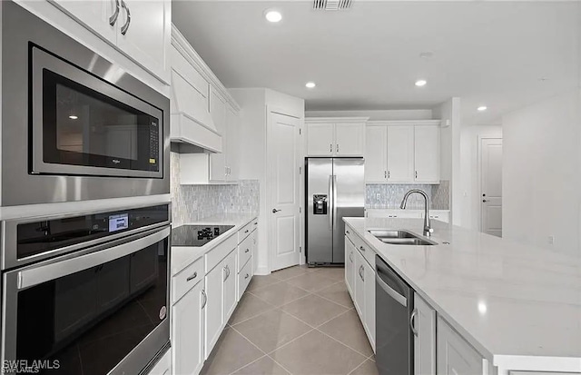 kitchen featuring sink, tasteful backsplash, light tile patterned floors, appliances with stainless steel finishes, and white cabinets