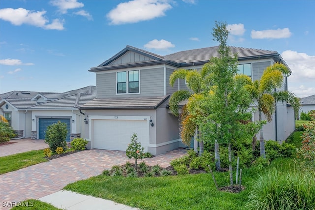 view of front of home featuring a tile roof, decorative driveway, an attached garage, and stucco siding