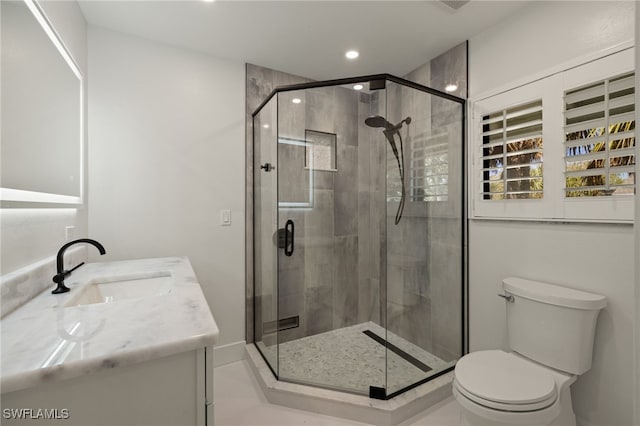 bathroom with vanity, a shower with shower door, and toilet