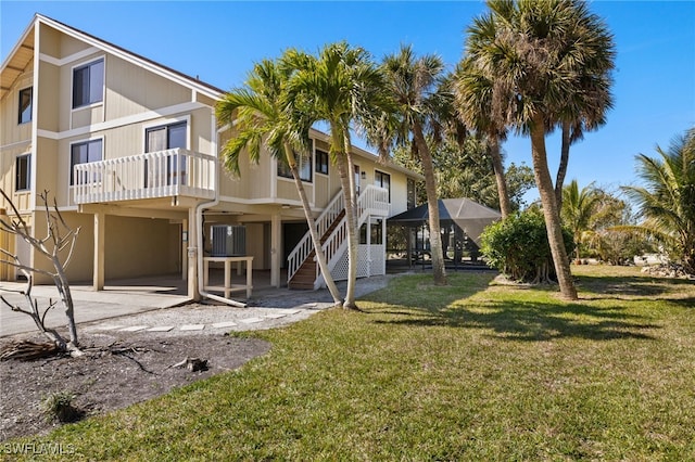 rear view of property with a lawn and central air condition unit