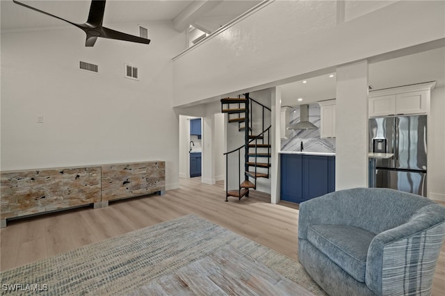 living room with ceiling fan, high vaulted ceiling, and light hardwood / wood-style flooring