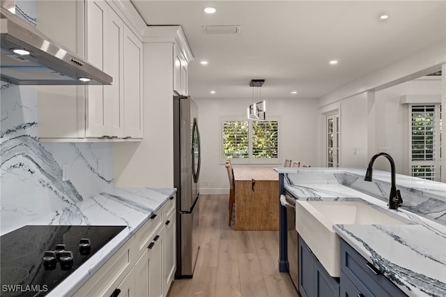 kitchen featuring hanging light fixtures, white cabinetry, appliances with stainless steel finishes, and exhaust hood