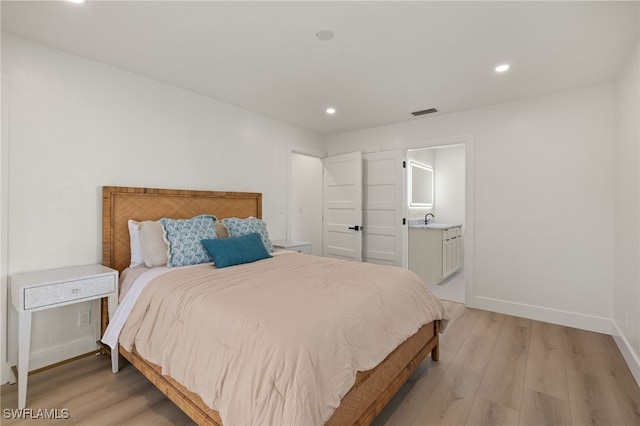 bedroom featuring sink, connected bathroom, and light hardwood / wood-style floors