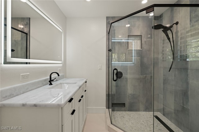 bathroom featuring a shower with door and vanity