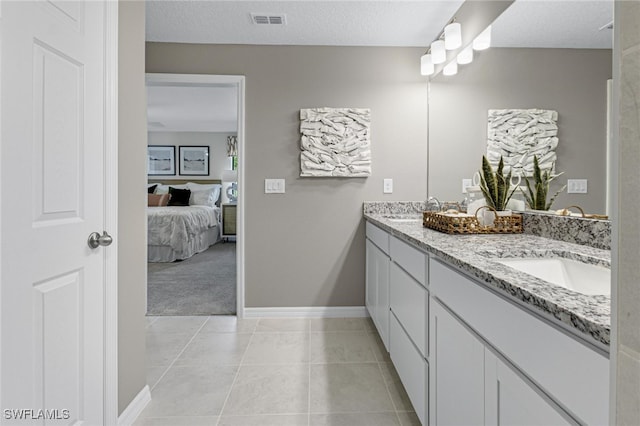 bathroom with a textured ceiling, tile patterned floors, and vanity