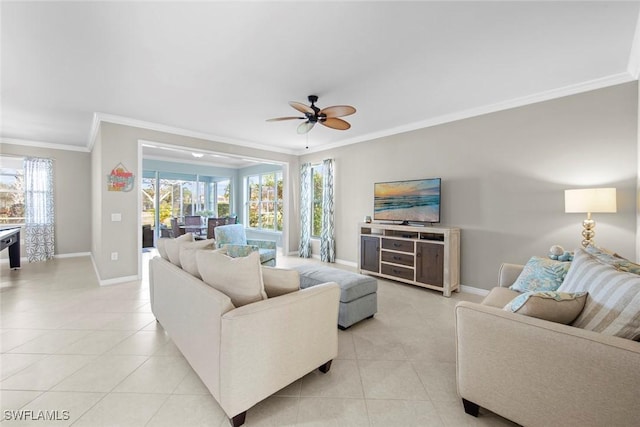 living area featuring light tile patterned floors, ornamental molding, a ceiling fan, and baseboards