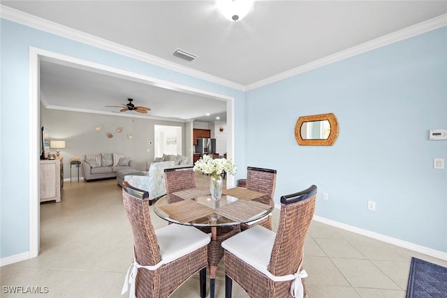 dining room with light tile patterned floors, a ceiling fan, visible vents, baseboards, and ornamental molding