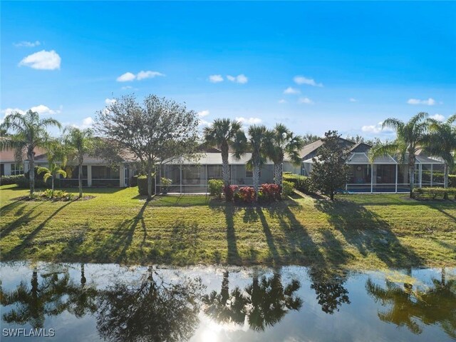 rear view of property featuring a water view and a lawn