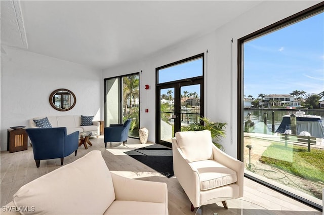 living room featuring light hardwood / wood-style flooring, french doors, and a water view