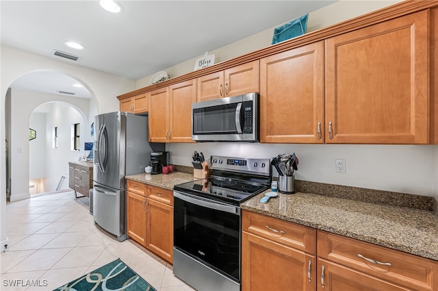 kitchen featuring stainless steel appliances, light tile patterned floors, and stone counters