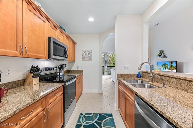 kitchen with light stone counters, appliances with stainless steel finishes, sink, and light tile patterned floors