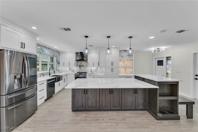 kitchen with a large island, appliances with stainless steel finishes, white cabinetry, light stone countertops, and wall chimney exhaust hood