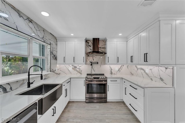 kitchen with wall chimney range hood, sink, appliances with stainless steel finishes, white cabinets, and decorative backsplash