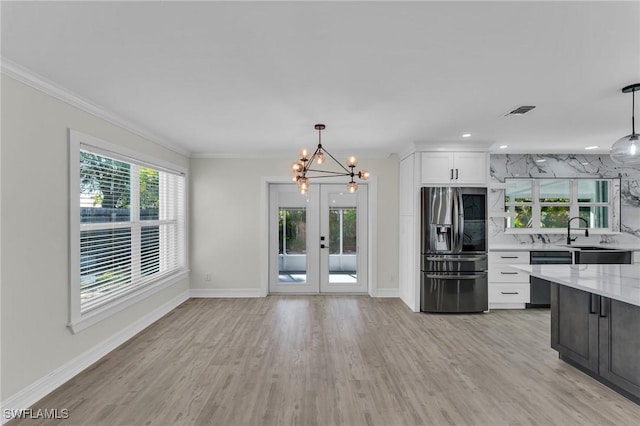 kitchen with dishwashing machine, decorative light fixtures, stainless steel fridge, and white cabinets