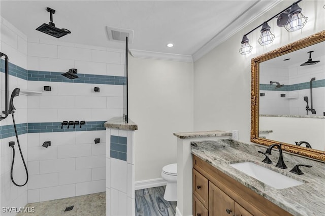 bathroom with crown molding, a tile shower, vanity, and toilet