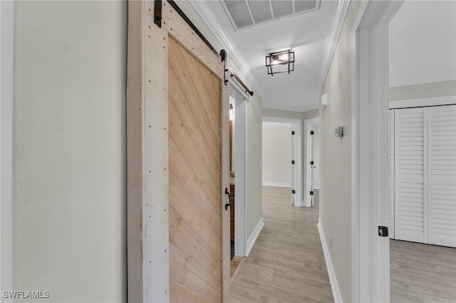 hall with crown molding, a barn door, and light wood-type flooring