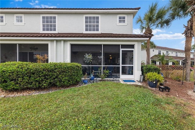 rear view of property featuring a lawn and a sunroom