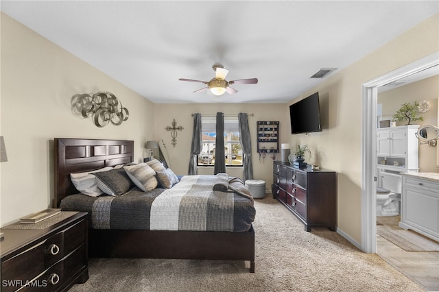 bedroom with light colored carpet, ceiling fan, and ensuite bath