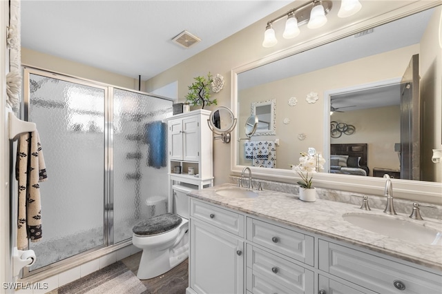 bathroom featuring vanity, hardwood / wood-style flooring, a shower with shower door, and toilet