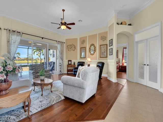 living room featuring crown molding, french doors, ceiling fan, and light wood-type flooring