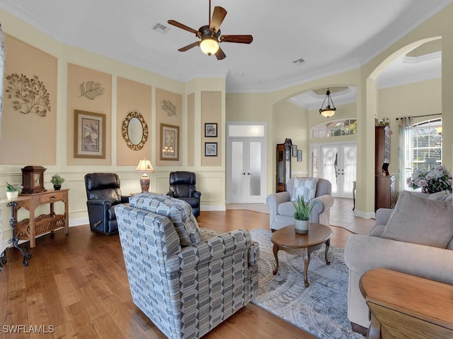 living room with crown molding, wood-type flooring, french doors, and ceiling fan