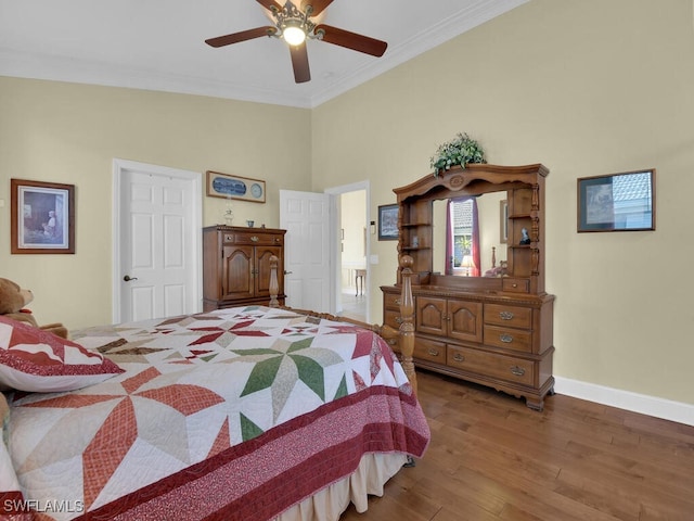 bedroom featuring ornamental molding, wood-type flooring, ceiling fan, and a towering ceiling