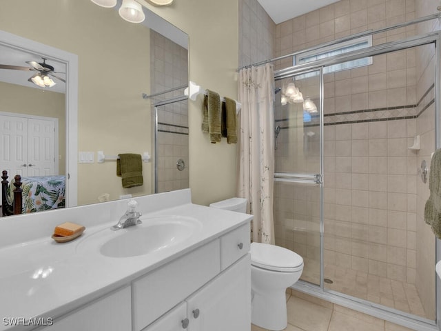 bathroom with tile patterned floors, toilet, vanity, a shower with door, and ceiling fan