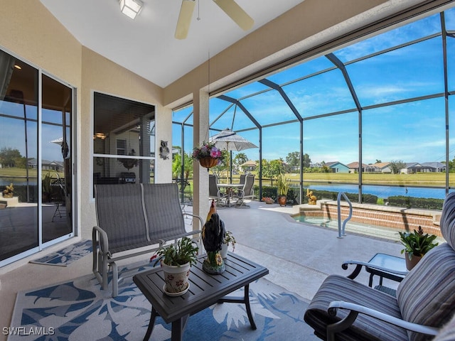 view of patio featuring a water view, ceiling fan, and glass enclosure