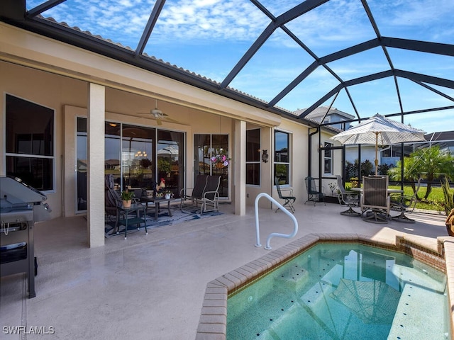 view of swimming pool with ceiling fan, a patio, and glass enclosure