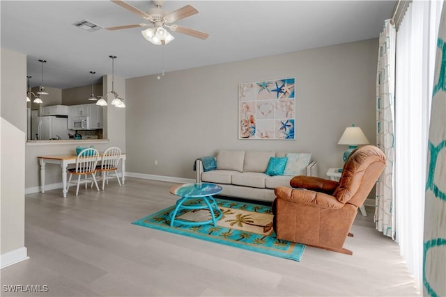 living room featuring light wood-type flooring and ceiling fan