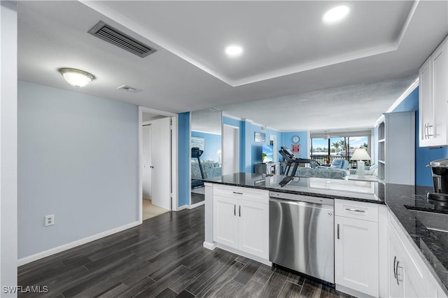 kitchen featuring white cabinetry, dark stone countertops, dark hardwood / wood-style flooring, stainless steel dishwasher, and a raised ceiling