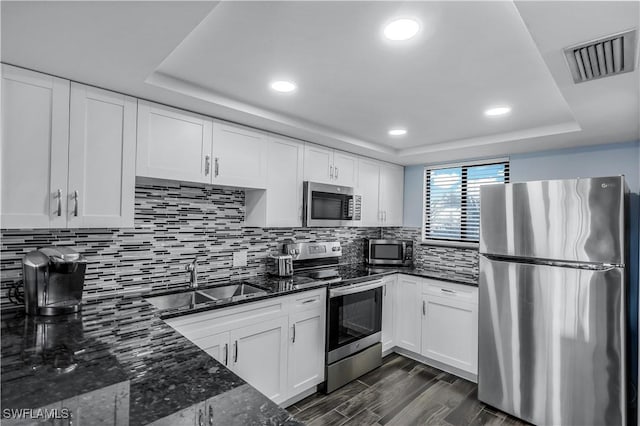 kitchen featuring sink, white cabinetry, tasteful backsplash, dark stone countertops, and stainless steel appliances