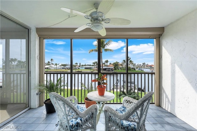 sunroom featuring ceiling fan and a water view