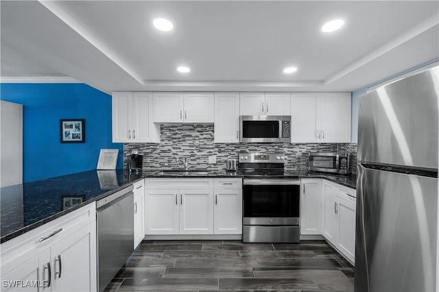 kitchen featuring white cabinetry, sink, dark stone counters, stainless steel appliances, and dark wood-type flooring