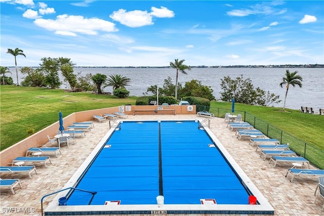 view of swimming pool with a water view, a patio area, and a lawn