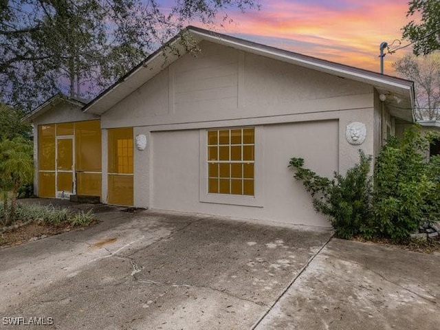 property exterior at dusk with a patio area and a sunroom