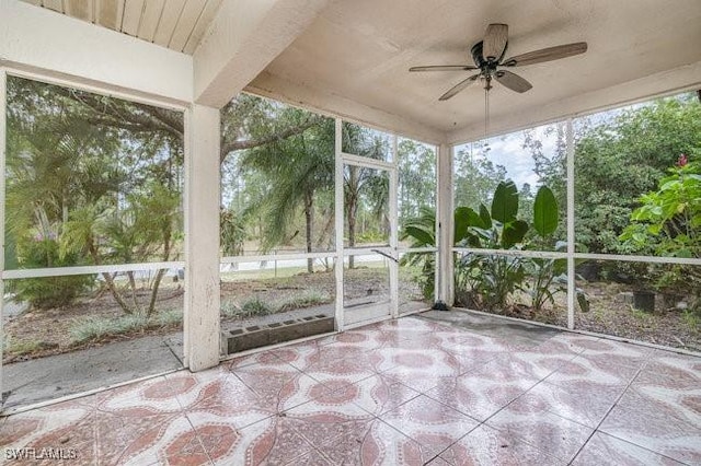 unfurnished sunroom featuring beamed ceiling and ceiling fan