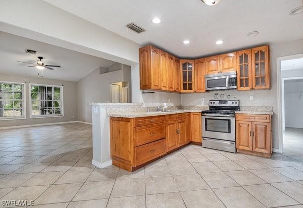 kitchen featuring ceiling fan, light tile patterned floors, backsplash, and appliances with stainless steel finishes