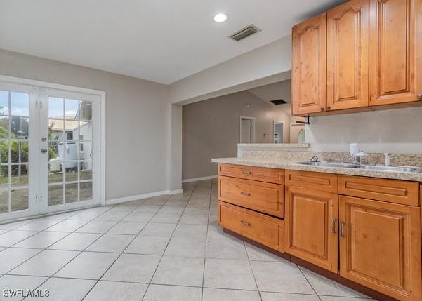 kitchen with sink, french doors, light stone countertops, and light tile patterned floors