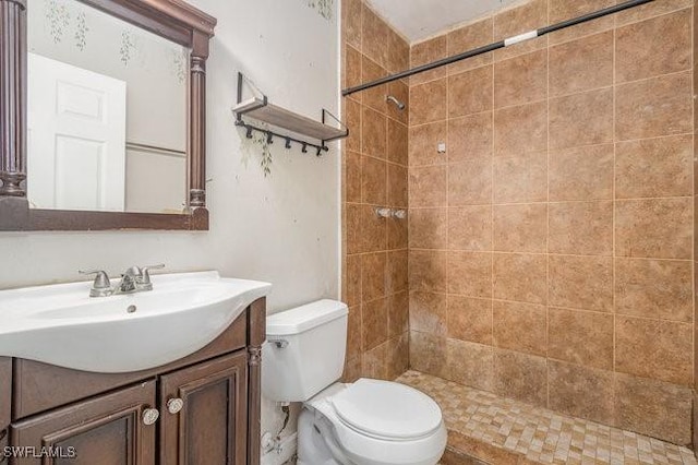 bathroom with tiled shower, toilet, and vanity