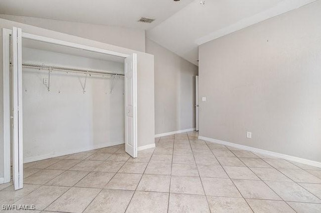 unfurnished bedroom featuring a closet, light tile patterned floors, and lofted ceiling