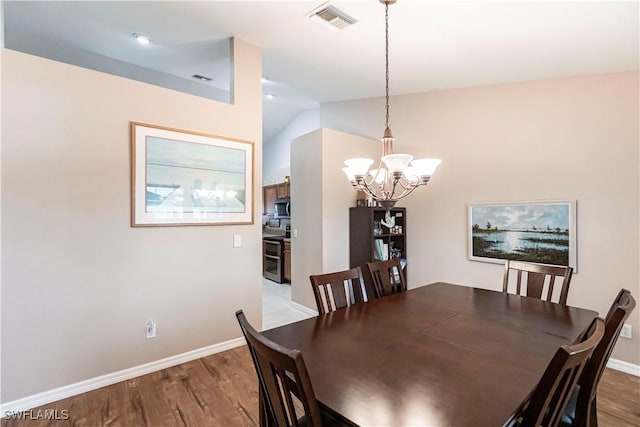 dining space featuring light hardwood / wood-style flooring, vaulted ceiling, and an inviting chandelier