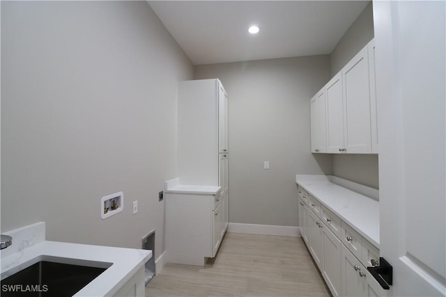 washroom featuring sink, cabinets, light hardwood / wood-style floors, hookup for a washing machine, and hookup for an electric dryer