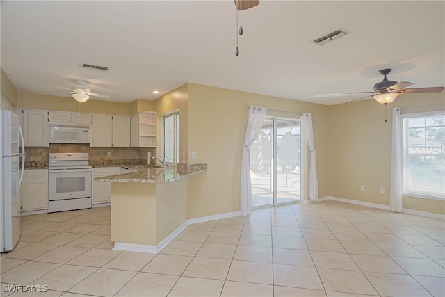 kitchen with white appliances, tasteful backsplash, light stone countertops, white cabinets, and kitchen peninsula