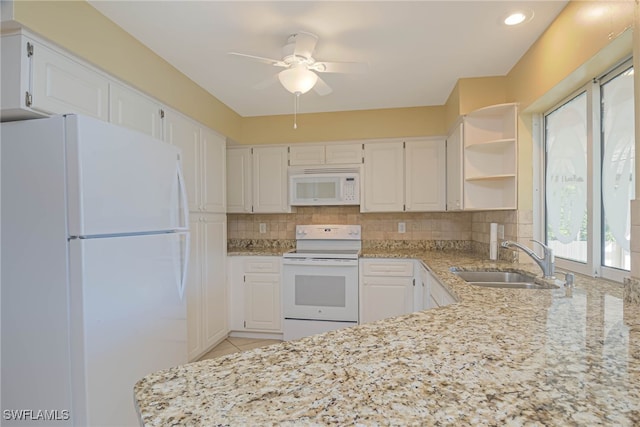 kitchen featuring sink, light stone counters, white cabinets, and white appliances