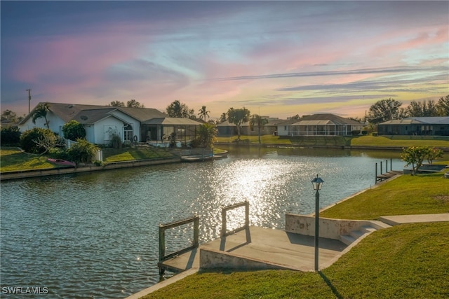 view of dock with a water view and a yard